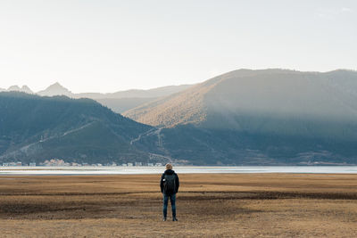 Rear view of man standing on mountain against sky