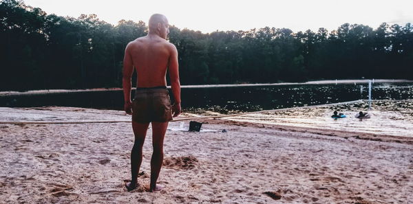 Rear view of shirtless man walking on shore