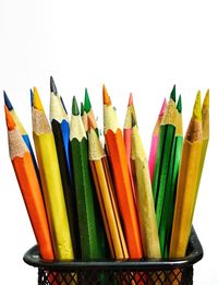 Close-up of colored pencils in desk organizer against white background