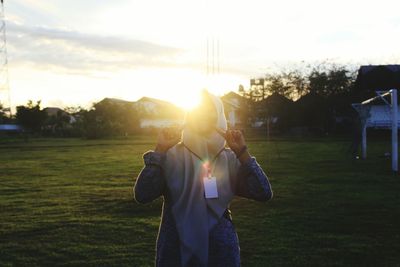 Rear view of man playing soccer on field against sky during sunset