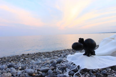 Close-up of pebbles on beach against sky during sunset