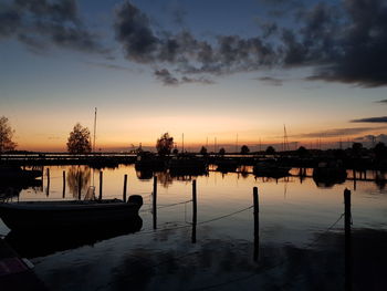 Boats moored at harbor against sky during sunset