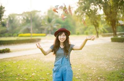 Portrait of young woman throwing fallen leaves