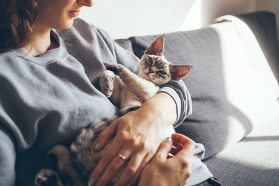 Midsection of woman with cat relaxing on sofa at home