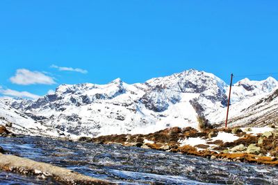 Scenic view of snowcapped mountains against blue sky