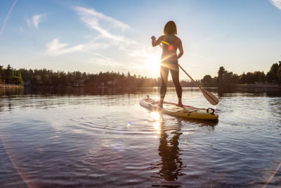 Full length of man on lake against sky during sunset