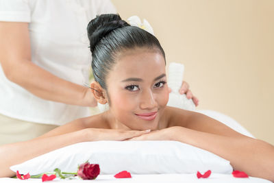 Midsection of masseuse giving massage to young woman relaxing at spa