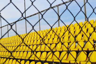 Close-up of yellow chainlink fence against sky