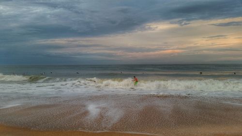 Scenic view of beach against cloudy sky