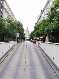 Road by buildings in city against sky