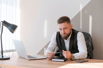 Handsome businessman is working with laptop in office, in business clothes