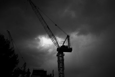 Low angle view of silhouette crane against sky