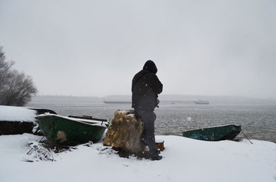 Man standing on snow covered land against sky