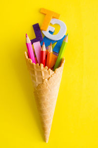 Close-up of multi colored pencils over yellow background