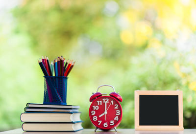 Close-up of colored pencils in desk organizer with books and alarm clock at home