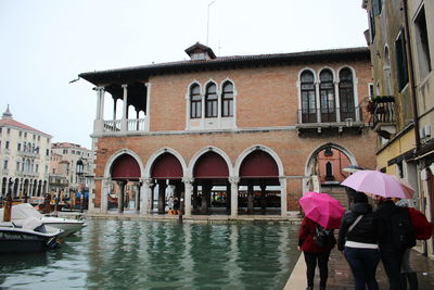 People on wet canal in city during rainy season