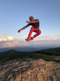 Full length of shirtless man jumping against sky