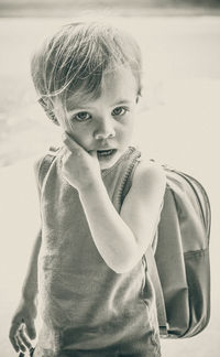 Portrait of girl biting thumb while standing with backpack