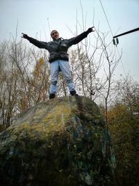 Low angle view of person standing on tree against sky