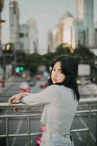 Side view of woman standing against railing in city