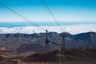 Overhead cable car over mountains against sky