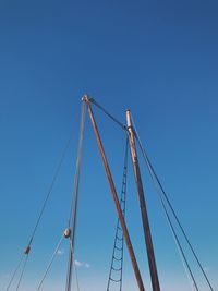 Low angle view of ship cables against clear blue sky