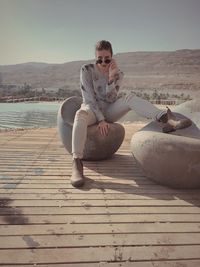 Portrait of woman sitting on seat against sea