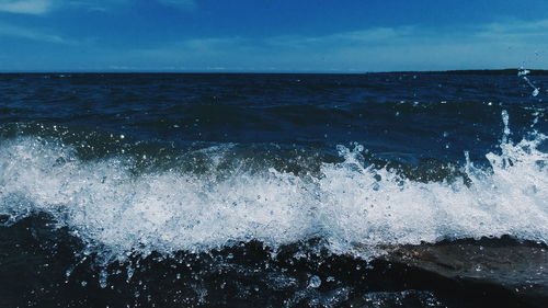 Scenic view of sea waves splashing against blue sky