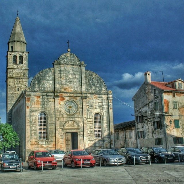 building exterior, architecture, built structure, car, transportation, mode of transport, land vehicle, sky, church, religion, place of worship, street, spirituality, city, travel, cloud - sky, cathedral, road