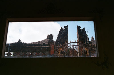 View of trees and buildings against sky seen through window