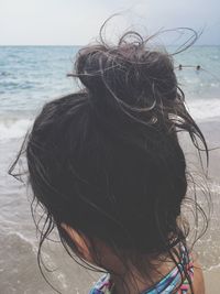 Rear view of woman at beach against sky