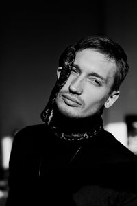 Portrait of young man holding snake at home