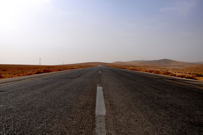 Road amidst field against sky