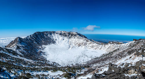 Scenic view of snowcapped mountains against blue sky