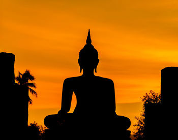 Silhouette statue against sky during sunset