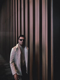 Young man wearing sunglasses standing against wall