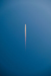 Low angle view of airplane flying against clear blue sky
