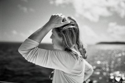 Woman with hand in hair against sea