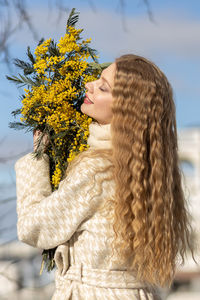 A woman with a bouquet of acacia flowers. the concept of the spring - march 8, easter, women's day.