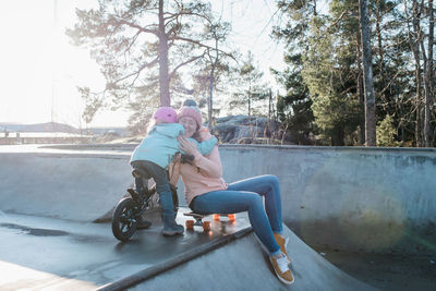 Mom and her daughter hugging whilst playing in a skatepark outside