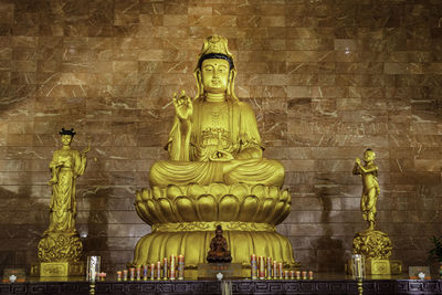 Statue of buddha against brick wall of building