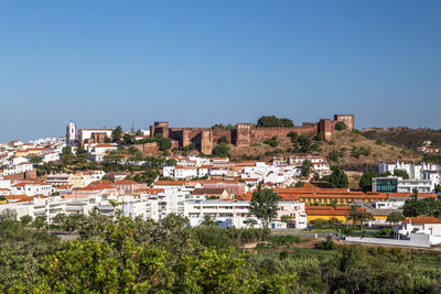 Buildings in city against clear blue sky