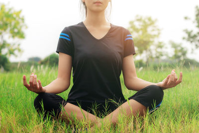 Midsection of woman sitting on field