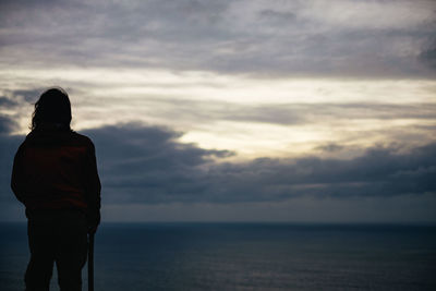 Rear view of man standing in sea against sky