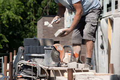 Masonry worker the bricklayer makes the facade of the house from gray bricks