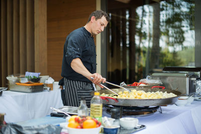 Man chef cook frying potatoes and vegetables traditional dish of street food on streets of europe