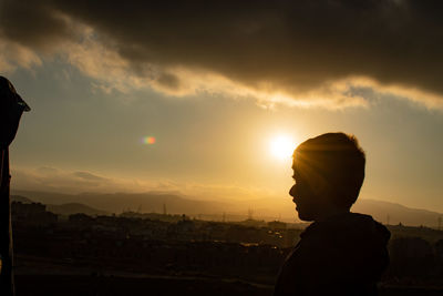 Side view of silhouette boy against sky during sunset