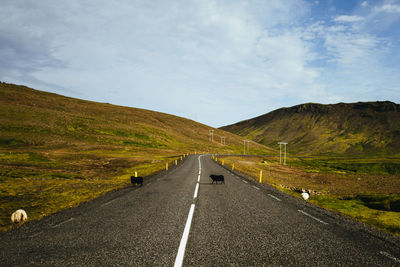 Road leading towards mountains against sky