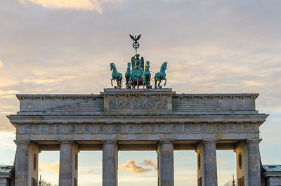 Low angle view of brandenburg gate against cloudy sky during twilight, berlin, germany