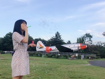 Side view of woman standing on field against sky